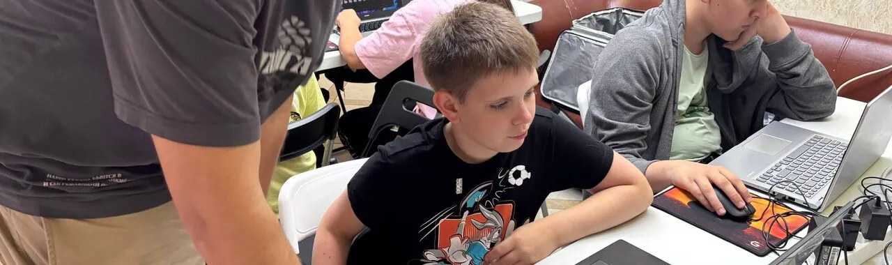 Занятие по созданию игр: преподаватель помогает школьнику за ноутбуком